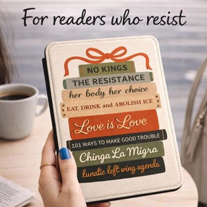 Puede incluir: Una funda de lector electrónico de color crema con un diseño de pila de lomos de libros. Los lomos presentan frases como "Love is Love" y "The Resistance". Un lazo rojo adorna la parte superior. El texto "For readers who resist" está en la parte superior.