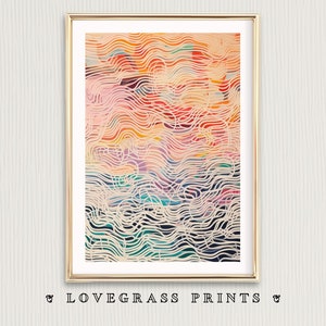 May include: Framed abstract art print with a gold frame. The artwork features a colorful, wavy pattern in shades of pink, orange, yellow, and teal, overlaid with a cream-colored, wave-like design. The text "& LOVEGRASS PRINTS &" is at the bottom.