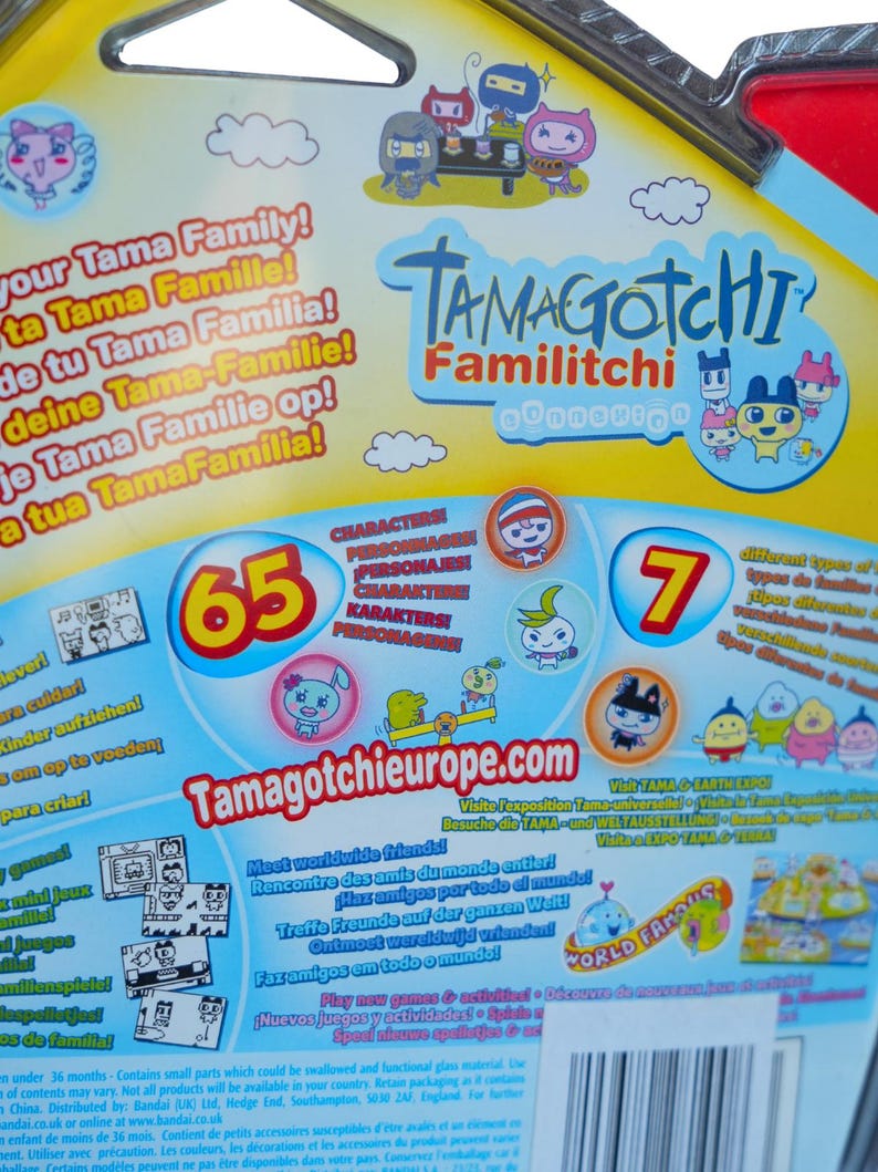 K&ouml;nnte beinhalten: Eine Tamagotchi Familitchi-Verpackung mit farbenfrohen Grafiken und Text. Die Verpackung zeigt verschiedene Zeichentrickfiguren, die Zahl 65 und den Text "World Famous". Die Website Tamagotchieurope.com ist ebenfalls zu sehen.