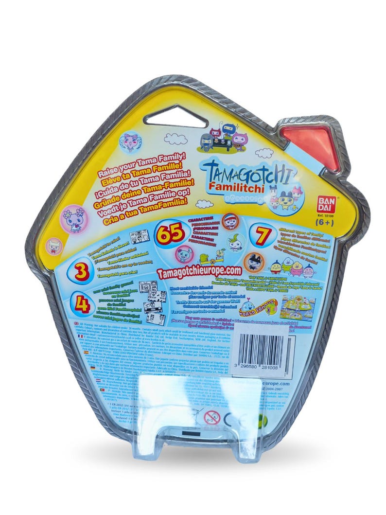 K&ouml;nnte beinhalten: Die R&uuml;ckseite einer Tamagotchi Familitchi-Spielzeugverpackung. Die Verpackung hat die Form eines Hauses und zeigt farbenfrohe Grafiken, darunter Zeichentrickfiguren und den Text "Raise your Tama Family!". Der Text "Tamagotchi Familitchi" und das Bandai-Logo sind ebenfalls enthalten.