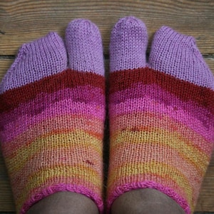 May include: A pair of colorful toe socks, featuring a gradient of colors from yellow to pink to red and purple. The socks are knitted and appear to be handmade, with each toe individually encased. The socks are on a wooden surface.