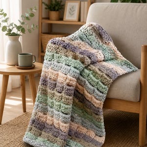 May include: A handmade crochet blanket in pastel colors of green, lavender, beige, and blue. The blanket is draped over a neutral-toned armchair. The textured pattern and soft color palette create a cozy, inviting aesthetic, perfect for home decor.