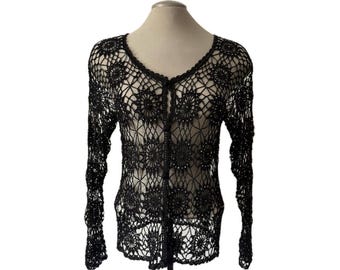 May include: A black long-sleeve cardigan featuring an intricate openwork crochet pattern with circular floral motifs throughout. The garment has a V-neckline and a front button closure with small, matching black buttons along the center placket.