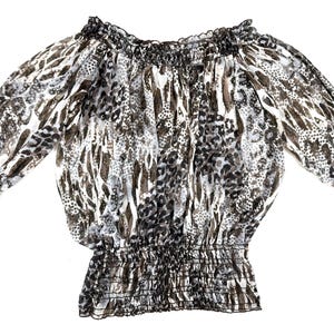May include: A sheer, off-the-shoulder blouse with a gathered neckline and waist. The long sleeves have elastic cuffs. The fabric features a pattern of black, gray, and brown animal print designs on a white background.