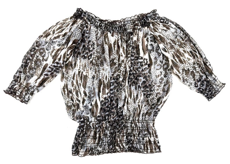 May include: A sheer, off-the-shoulder blouse with a gathered neckline and waist. The long sleeves have elastic cuffs. The fabric features a pattern of black, gray, and brown animal print designs on a white background.