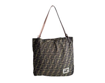 May include: A brown and black tote bag featuring a repeating F-logo pattern across the fabric surface. The bag includes a single shoulder strap and a rectangular silver-toned metal plaque with an embossed F-logo detail on the lower right corner.