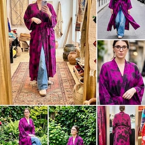 Può includere: Una lunga vestaglia fluida nei toni del magenta e del nero, con un motivo tie-dye. La vestaglia ha maniche ampie e viene indossata aperta, rivelando jeans blu. L'indumento è realizzato in un tessuto morbido e fluido, perfetto per la stratificazione.