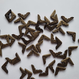 May include: A large quantity of antique gold corner protectors with a decorative design. The corner protectors are made of metal and have a vintage look.