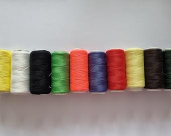 May include: Ten spools of thread in various colors, including yellow, white, black, green, orange, blue, and red.