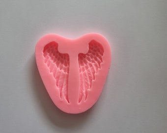 May include: Pink silicone mold for baking angel wings. The mold is heart-shaped and features a detailed design of two angel wings.