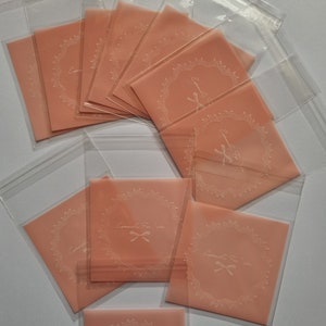 Puede incluir: Una colección de bolsas de plástico transparente, cada una con una tarjeta de color melocotón. Las tarjetas presentan un borde decorativo blanco, el texto "Especially For You" y un lazo. Las bolsas están selladas con cierre de cremallera.