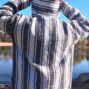 Peut inclure: Un sweat à capuche rayé blanc et noir avec une coupe ample. Le sweat-shirt est fait d'un tissu doux et confortable et a une capuche avec cordon de serrage.
