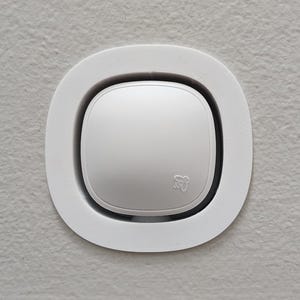 Puede incluir: Un soporte de techo redondo blanco con un dispositivo circular blanco en el centro. El dispositivo tiene un pequeño logotipo de abeja en él.