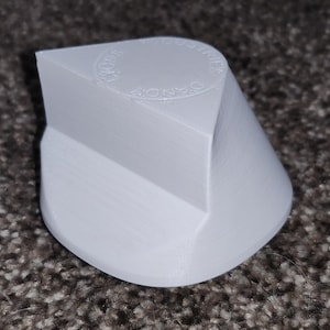 Puede incluir: Objeto de plástico blanco en forma de diamante con las palabras "The World's Finest Diamonds" en relieve en la parte superior.