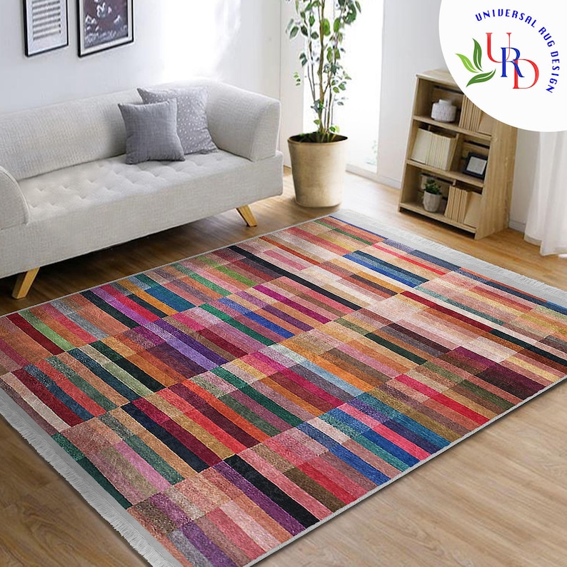 May include: Multicolored striped area rug with a white fringe border. The rug is made of a soft, woven material and features a geometric pattern of horizontal stripes in various shades of red, orange, yellow, green, blue, purple, and brown.