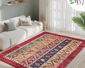 May include: A red, blue, yellow, and green patterned area rug with a geometric design. The rug is laid out on a wooden floor in a living room setting with a white couch in the background.