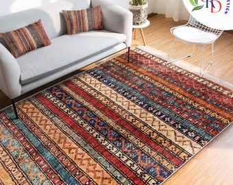May include: A colorful, striped rug with intricate patterns in shades of red, orange, blue, and beige. The rug is laid out on a wooden floor in a living room setting.