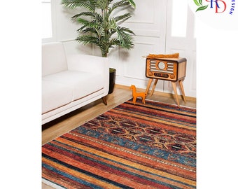 May include: A colorful striped rug with a geometric pattern in the center. The rug is in a living room setting with a white sofa, a potted plant, and a vintage radio.