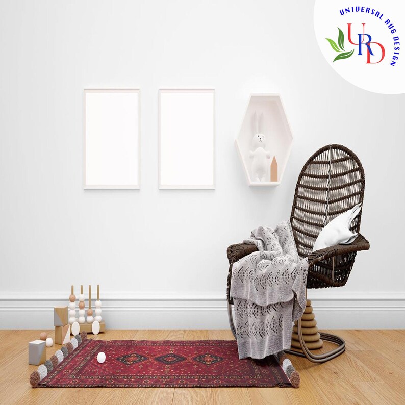 May include: A red and cream patterned rug with fringe on the edges. The rug is in a room with a white wicker chair, a white rabbit toy, and two white picture frames.