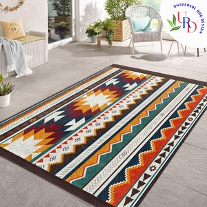 May include: A colorful geometric patterned rug with a brown border. The rug has a white background with stripes of orange, yellow, red, blue, and green. The rug is made of a soft, durable material and is perfect for adding a touch of style to any room.