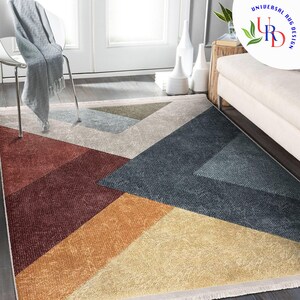 May include: A rectangular area rug with a geometric design. The rug features large triangular and rectangular shapes in shades of red, orange, yellow, blue, and beige. The rug has a fringed edge and is placed on a wooden floor.