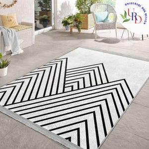 May include: A rectangular rug with a striking geometric pattern. The rug has a white base with a bold black design of angled lines and zigzags. It has a fringed edge and is suitable for indoor use, measuring approximately 160cm x 230cm.