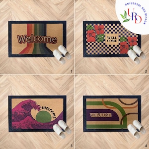 Könnte beinhalten: Vier verschiedene Willkommens-Fußmatten mit verschiedenen Designs. Die erste Fußmatte hat ein Regenbogen-Design mit dem Wort "Welcome" in der Mitte. Die zweite Fußmatte hat ein kariertes Muster mit roten Blumen und den Worten "Well Come". Die dritte Fußmatte hat ein Wellendesign mit dem Wort "Welcome" in einem Kreis. Die vierte Fußmatte hat ein geometrisches Design mit dem Wort "Welcome" in der Mitte.