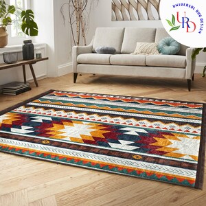 May include: A colorful geometric rug with a southwestern design. The rug features a variety of colors, including red, orange, yellow, green, and blue. The rug is laid out on a wooden floor in a living room setting.