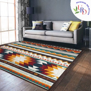 May include: A colorful geometric patterned rug with a brown fringe. The rug is laid out on a hardwood floor in front of a gray sofa with pillows.