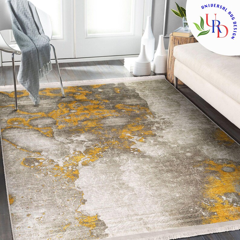 May include: A rectangular area rug with a distressed design. The rug features a blend of gray, white, and yellow hues, creating an abstract, marbled effect. The rug has a fringed edge and is suitable for living rooms and bedrooms.