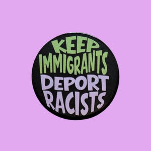 May include: A circular pin-back button with a black background. The text 'KEEP IMMIGRANTS' is printed in light green, while the text 'DEPORT RACISTS' is printed in light purple. The lettering is in a bold, sans-serif, slightly uneven font style.