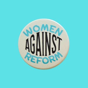 May include: A circular, cream-coloured badge featuring the text "WOMEN AGAINST REFORM" in black and light blue. The background is a solid, bright blue.