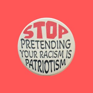 May include: A circular pinback button with a cream-coloured background. The word STOP is printed in large, bold red capital letters at the top. Below, the black text reads PRETENDING YOUR RACISM IS PATRIOTISM in a stylised, slightly curved font.