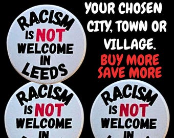 May include: White round badges with the text "RACISM IS NOT WELCOME IN" followed by the city names Leeds, Bristol, and London. The word "NOT" is in red. The image also includes the text "CUSTOMISE THESE BADGES TO YOUR CHOSEN CITY, TOWN OR VILLAGE."
