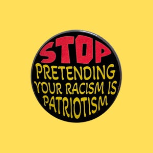 May include: A circular pinback button with a black background. The word STOP is printed in large red capital letters at the top. Below this, the yellow text reads PRETENDING YOUR RACISM IS PATRIOTISM in a stylised, rounded font.