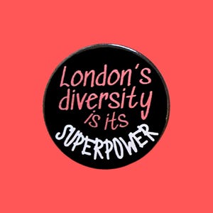 May include: A circular black badge with the words "London's diversity is its SUPERPOWER" in pink and white. The badge is set against a coral-coloured background.