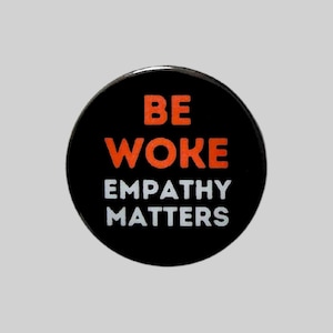 May include: Black button with white text that reads "BE WOKE EMPATHY MATTERS" and orange text that reads "WOKE".