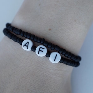 May include: A black beaded bracelet with white letter beads spelling out "AFI".