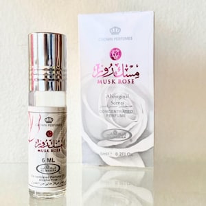 May include: A clear glass perfume bottle with a silver cap and a white label, next to a white box. The label and box feature the text "MUSK ROSE" in English and Arabic, with "Aboriginal Scents" and "Concentrated Perfume" also visible. The bottle contains 6 ml.