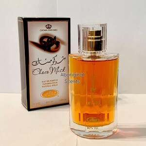 May include: A perfume bottle and box set. The bottle contains a golden-brown liquid and has a clear cap. The box is black with gold accents and features the text "Choco Musk" and "Crown Perfumes". The text "Aboriginal Scents" is also visible.
