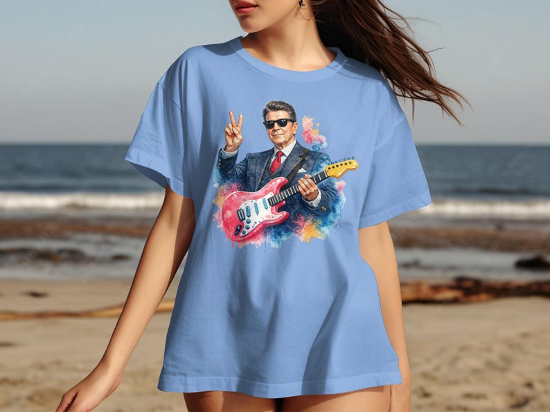 Light blue t-shirt with Ronald Reagan playing a pink guitar.