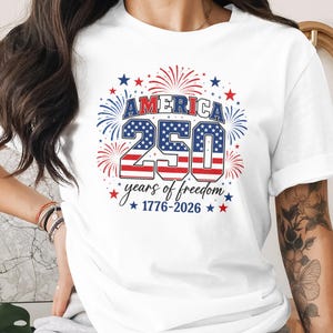 White t-shirt with "America 250 years of freedom 1776-2026" text and fireworks.