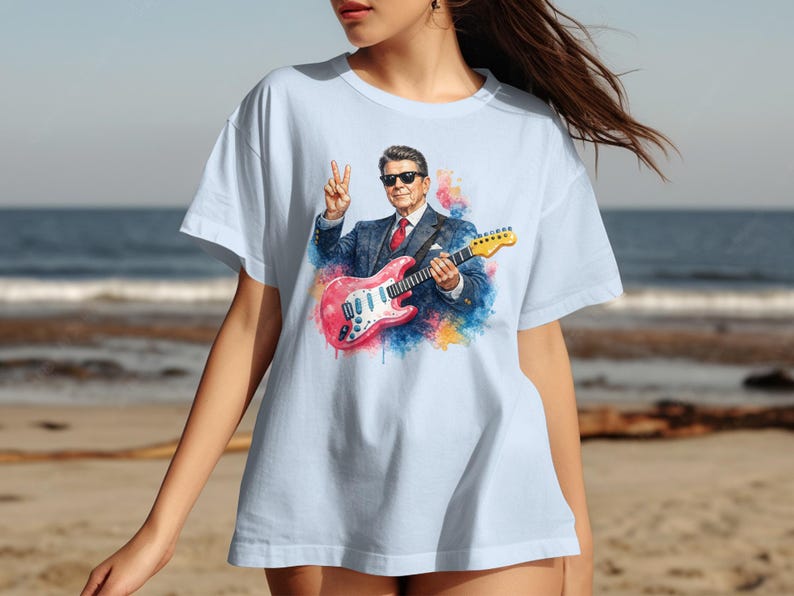 T-shirt with watercolor painting of Ronald Reagan playing guitar on beach.