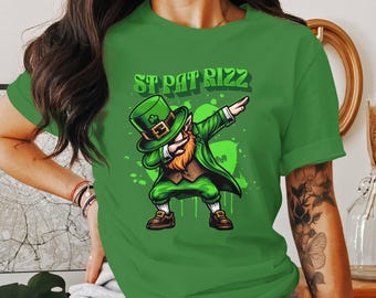 Puede incluir: Camiseta verde con un duende de dibujos animados haciendo el dab y el texto "St Pat Rizz".