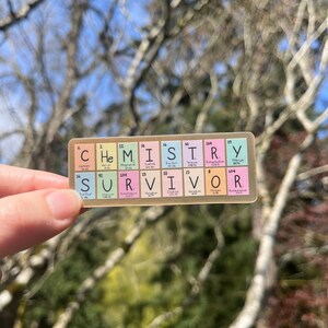 May include: A sticker with the word "CHEMISTRY" spelled out using the chemical element symbols for each letter. The word "SURVIVOR" is spelled out below using the same method.