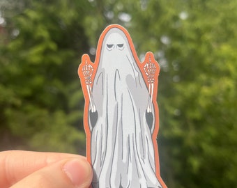 May include: A white ghost with a grumpy expression is giving the middle finger with both hands. The ghost's hands are skeletal and the sticker has an orange outline.