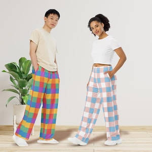 May include: Two people wearing colorful plaid pajama pants. One pair features a rainbow grid pattern, while the other has a pink, blue, and white checkered design. Both individuals are wearing casual tops and white shoes.