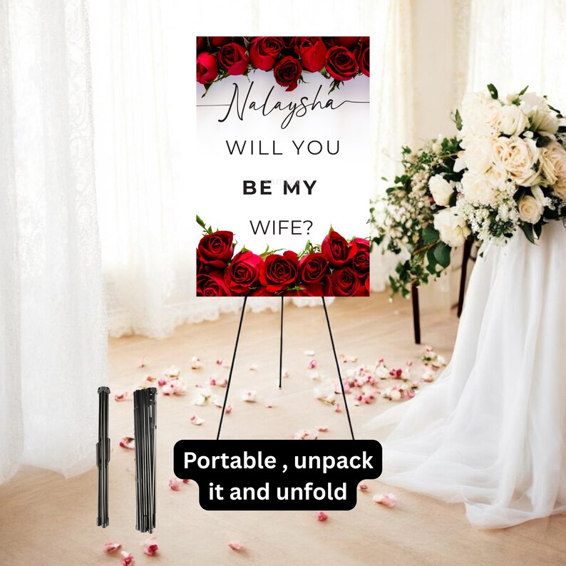 May include: A white sign with the text "Nalaysha, will you be my wife?" is framed by red roses. The sign is displayed on a black easel. The words "Portable, unpack it and unfold" are written on a black rectangle.