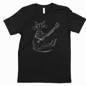 ギターを弾くクールな猫のTシャツ、ユニークなミュージシャン猫シャツ