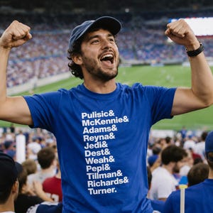 May include: A royal blue short-sleeved t-shirt featuring a vertical list of white printed names including Pulisic, McKennie, Adams, Reyna, Jedi, Dest, Weah, Pepi, Tillman, Richards, and Turner, each separated by an ampersand symbol.
